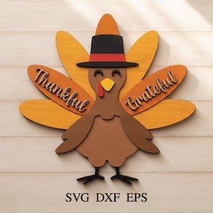 May include: A layered wooden turkey cutout featuring a black hat with a red band, a yellow beak, and a red wattle. The turkey has orange and yellow tail feathers with the words Thankful and Grateful in script. Text at the bottom reads SVG DXF EPS.