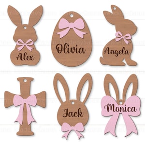 Può includere: Sei etichette pasquali in legno con fiocchi rosa e nomi. Le etichette hanno la forma di un coniglio, un uovo, una croce e una testa di coniglio. I nomi sulle etichette sono Alex, Olivia, Angela, Jack e Monica.