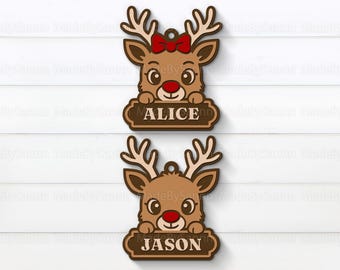 Könnte beinhalten: Zwei hölzerne Rentier-Ornamente. Eines hat eine rote Schleife und den Namen "ALICE" auf einem Banner. Das andere hat den Namen "JASON" auf einem Banner. Beide haben Geweihe, rote Nasen und sind braun.