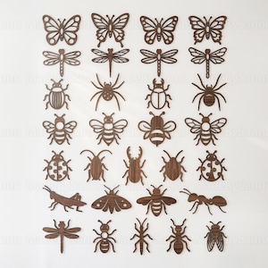 以下が含まれることがあります： 蝶、トンボ、カブトムシ、ハチ、アリなど、木製の昆虫の切り抜きコレクション。昆虫はさまざまなサイズと形状で、すべて濃い茶色の木の色合いです。切り抜きは白い背景に配置されています。