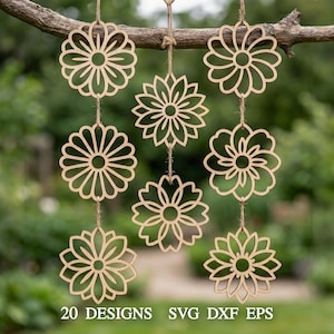 May include: Nine laser-cut wooden flower ornaments hanging from a tree branch. The ornaments are various floral designs, suspended by twine. The text "20 DESIGNS SVG DXF EPS" is visible at the bottom of the image. The background is blurred green foliage.