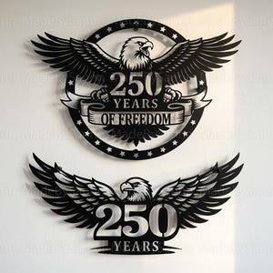 May include: Two black metal wall art pieces featuring eagles with outstretched wings. The top piece is circular with the text "250 YEARS OF FREEDOM." The bottom piece has the text "250 YEARS."