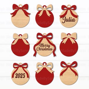 Può includere: Nove ornamenti natalizi in legno con dettagli rossi e beige. Alcuni ornamenti hanno un fiocco in cima e un nastro rosso. Un ornamento dice "Julia", un altro dice "Merry Christmas" e un altro dice "2025".