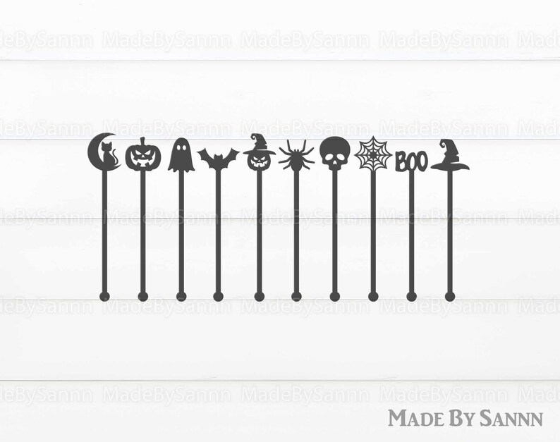May include: Set of ten black Halloween-themed cocktail stirrers. The stirrers feature a variety of designs, including a crescent moon, a cat, a pumpkin, a ghost, a bat, a witch's hat, a spider, a skull, a spiderweb, and the word "BOO".