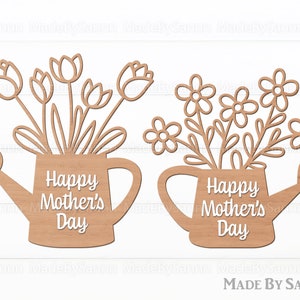 Könnte beinhalten: Zwei hölzerne Ausschnitte von Gießkannen mit Blumen. Die Gießkannen haben den Text "Happy Mother's Day" auf sich.