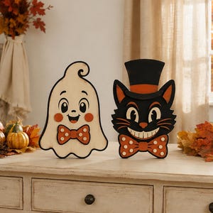 May include: Two wooden cutout decorations featuring a smiling cream-colored ghost with a polka-dot bow tie and a black cat wearing a top hat with an orange band and a matching polka-dot bow tie, both designed with a vintage-inspired aesthetic.