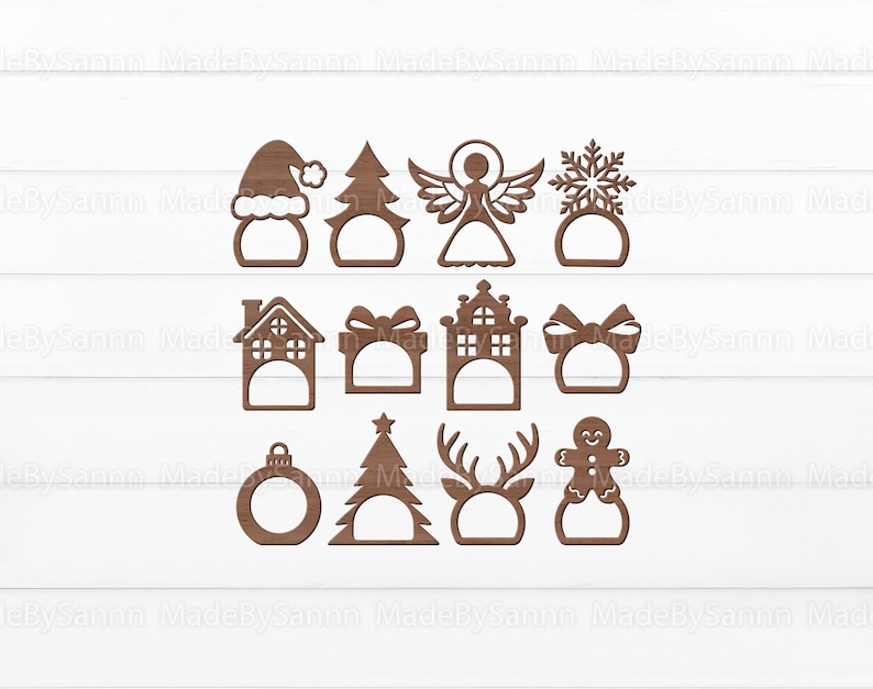 K&ouml;nnte beinhalten: Set mit 12 Weihnachts-Serviettenringen aus Holz mit verschiedenen Designs, darunter ein Weihnachtsbaum, ein Schneemann, ein Haus, eine Geschenkbox, eine Schneeflocke, ein Engel, ein Rentier, ein Lebkuchenmann und ein Ornament.