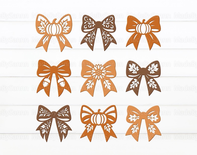 May include: Nine decorative wooden bows in shades of brown and orange, featuring fall-themed designs. The bows include pumpkin, acorn, and leaf motifs, perfect for autumn crafts and decorations. The bows are arranged on a white wooden surface.