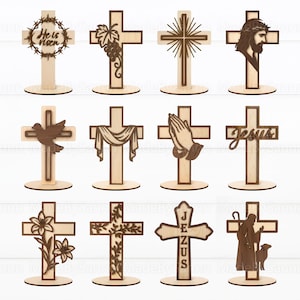 May include: A collection of twelve wooden crosses with various designs. Some crosses feature a crown of thorns, grapes, a dove, praying hands, and the word "Jesus." Each cross is mounted on a circular base, showcasing a natural wood grain.