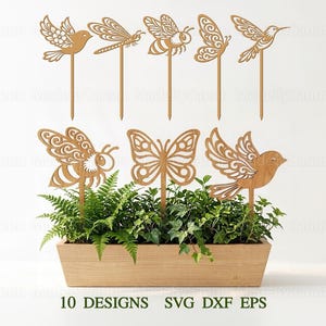 Könnte beinhalten: Holz-Gartenstecker mit Vogel-, Bienen-, Schmetterlings- und Libellen-Designs. Die Stecker sind in einem hölzernen Pflanzkasten mit Grünpflanzen platziert. Der Text "10 DESIGNS SVG DXF EPS" ist unten zu sehen.