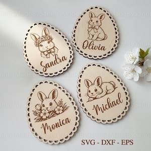 May include: Four wooden Easter egg decorations with scalloped edges. Each egg features a laser-cut bunny design and a name: Sandra, Olivia, Monica, and Michael. The ornaments are light brown and are suitable for Easter decorations.