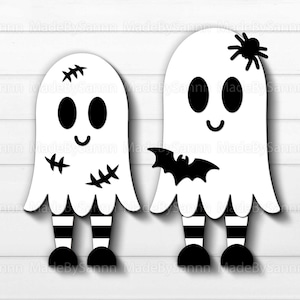 May include: Two white ghosts with black eyes and mouths, one with stitched seams and the other with a black spider on its head. Both ghosts have black and white striped legs and black shoes.