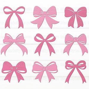 May include: Nine pink bows with different shapes and sizes. The bows are on a white wooden background.