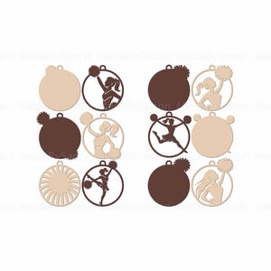 May include: A collection of wooden ornaments featuring cheerleading designs. The ornaments are circular with a small loop at the top for hanging. Some have a solid color, while others feature a cheerleader silhouette with pom-poms, in shades of brown and beige.