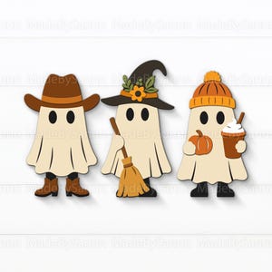 Puede incluir: Tres recortes de fantasmas de Halloween de madera. Un fantasma lleva un sombrero de vaquero y botas, otro un sombrero de bruja y sostiene una escoba, y el último lleva un gorro, una calabaza y un café.