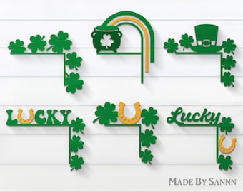 May include: Four different green shamrock corner designs with gold accents. The designs include a pot of gold, a leprechaun hat, a horseshoe, and the word "Lucky" with a horseshoe.