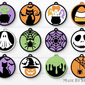 Puede incluir: Doce adornos redondos con tem&aacute;tica de Halloween con varios dise&ntilde;os, que incluyen un fantasma, una ara&ntilde;a, un sombrero de bruja y ma&iacute;z dulce. Los adornos son todos en blanco y negro con acentos de colores.