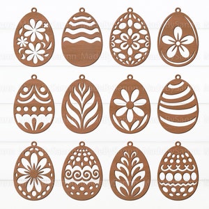 Pode incluir: Doze ornamentos de ovo de Páscoa de madeira com vários desenhos recortados, incluindo padrões florais, geométricos e ondulados. Os ornamentos são todos marrons e têm um furo na parte superior para pendurar.