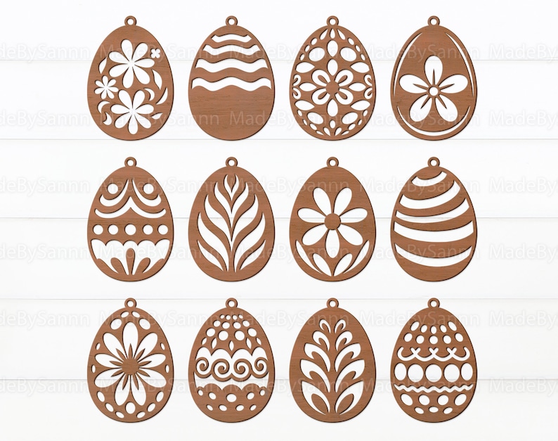 May include: Twelve wooden Easter egg ornaments with various cut-out designs, including floral, geometric, and wavy patterns. The ornaments are all brown and have a hole at the top for hanging.
