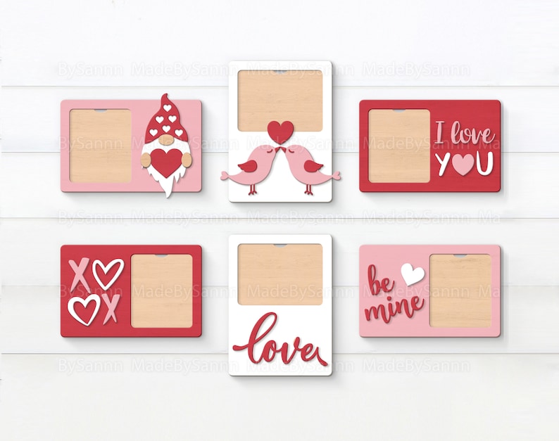 May include: Six Valentine's Day themed picture frames with different designs. The frames are made of wood and have a white, pink, or red background. The designs include a gnome, birds, hearts, and the words "I love you", "be mine", "love", and "XO".