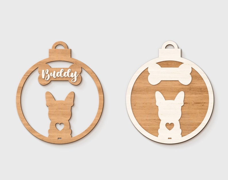 Pu&ograve; includere: Un ornamento natalizio in legno a forma di palla con una silhouette bianca di un cane e un osso con la parola "Buddy" su di esso.