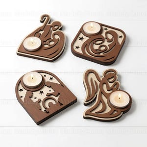 Puede incluir: Cuatro portavelas de madera con recortes de temática religiosa. Cada soporte tiene un diseño diferente, incluyendo un ángel, un pesebre y formas abstractas. Cada soporte tiene una vela de té encendida. Los soportes son marrones y beige.