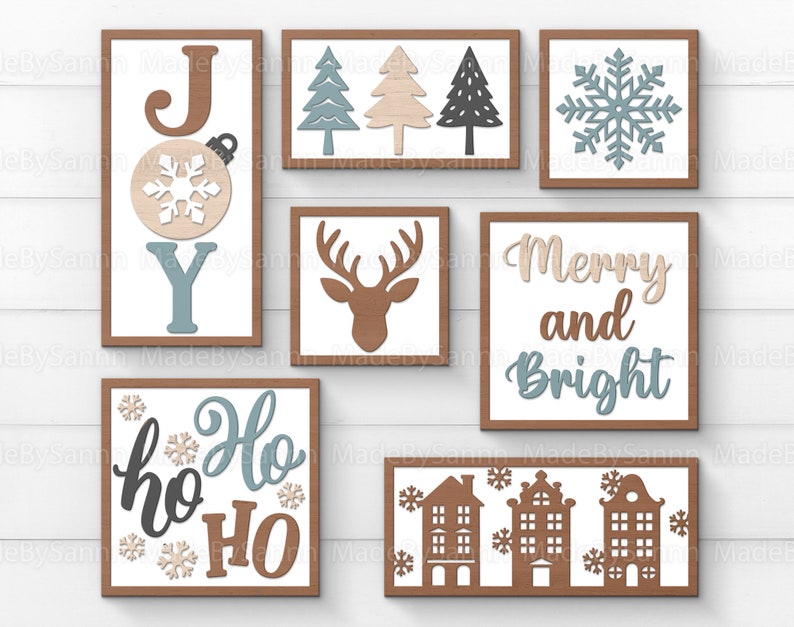 Peut inclure: Un ensemble de neuf panneaux de No&euml;l en bois sur le th&egrave;me de l'hiver. Les panneaux pr&eacute;sentent les mots "Joy", "Ho Ho HO", "Merry and Bright", ainsi qu'un flocon de neige, un cerf et une rang&eacute;e de maisons. Les panneaux sont peints dans des tons de brun, de bleu et de blanc.