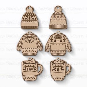 Op de afbeelding: Zes houten kerstversieringen in de vorm van een muts, trui en mok. De ornamenten zijn lichtbruin met ge&euml;tste ontwerpen van rendieren, bomen en sneeuwvlokken. Elk ornament heeft een klein gaatje om op te hangen.