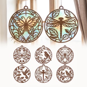 May include: A collection of brown, circular, decorative suncatchers. The suncatchers feature intricate cut-out designs of butterflies, dragonflies, and birds, surrounded by leaves and floral patterns. The suncatchers are hanging in front of a window.