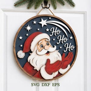 May include: A circular wooden wall sign featuring a layered Santa Claus design with a red hat, white beard, and red gloves. The dark blue background displays white stars, a shooting star, and the white text Ho Ho Ho. It hangs from a rope.