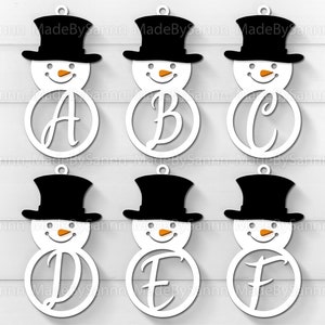 Puede incluir: Seis adornos de muñeco de nieve blancos con sombreros negros y narices naranjas. Cada muñeco de nieve tiene un círculo blanco con una letra del alfabeto en letra cursiva.