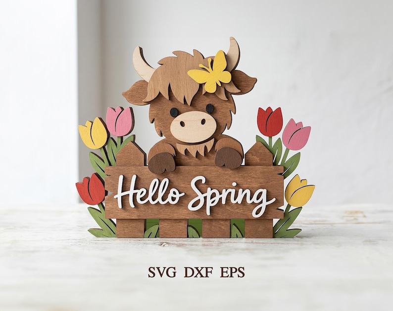 Peut inclure: D&eacute;coration printani&egrave;re en bois repr&eacute;sentant une vache des Highlands regardant par-dessus une cl&ocirc;ture avec l'inscription "Hello Spring". La vache a une fourrure brune, un papillon jaune et est entour&eacute;e de tulipes color&eacute;es. Un charmant accent saisonnier.