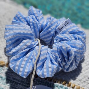 May include: Blue and white striped scrunchie with a white tag that says "Tidal Vibe".