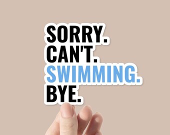 May include: A white sticker with the text "SORRY. CAN'T. SWIMMING. BYE." in black and light blue. The sticker is held by a person's hand against a neutral background.