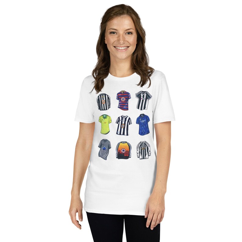 Puede incluir: Una camiseta blanca con un gr&aacute;fico de nueve camisetas de f&uacute;tbol diferentes. Las camisetas son de varios colores y dise&ntilde;os, incluyendo rayas blancas y negras, rayas azules y blancas y rayas rojas y blancas.