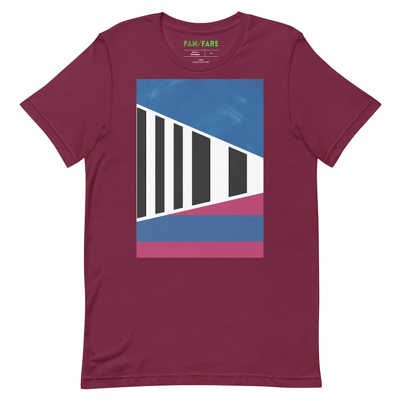 May include: A maroon t-shirt with a graphic design featuring a geometric pattern of black, white, blue, and pink shapes.
