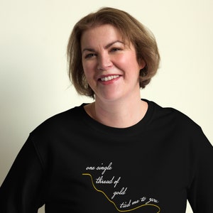 May include: A black sweatshirt with a gold thread design that reads "one single thread of gold tied me to you".