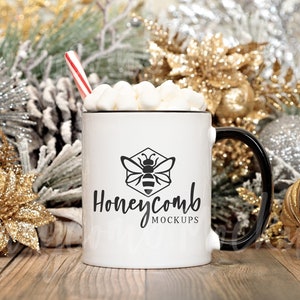 May include: White ceramic mug with a black handle and a black bee logo that says "Honeycomb Mockups". The mug is filled with marshmallows and a red and white candy cane.