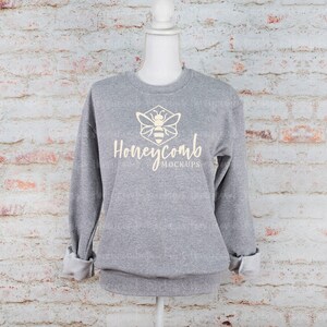 May include: A gray sweatshirt with a yellow bee logo and the text "Honeycomb Mockups" printed on the front.