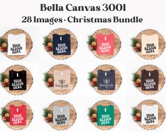 May include: A collection of twelve Bella Canvas 3001 t-shirts in various colors, each featuring the text 'YOUR DESIGN HERE' or 'Honeycomb Mockups', displayed on wooden rounds with Christmas greenery and dried orange slices.