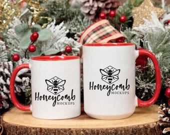 May include: Two white ceramic mugs with red interiors and red handles. Each mug features a black graphic of a bee inside a hexagon above the text Honeycomb MOCKUPS. The mugs are positioned side by side on a circular wooden surface.