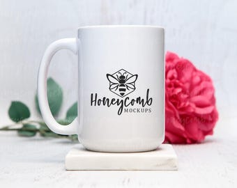 Könnte beinhalten: Ein weißer Keramikbecher mit einer schwarzen Grafik einer Biene in einem Sechseck über dem Text Honeycomb MOCKUPS. Der Becher hat einen geschwungenen Henkel und eine glatte Oberfläche, wobei das Design klar und zentriert auf der Vorderseite liegt.