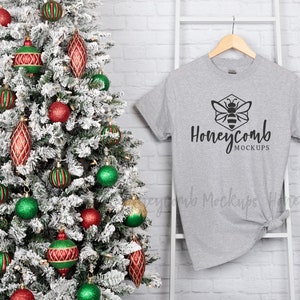 May include: A gray t-shirt with a black honeycomb design and the text "Honeycomb Mockups" on a white hanger in front of a Christmas tree with red and green ornaments.