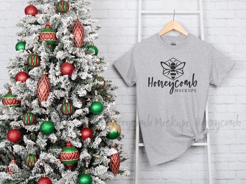 May include: A gray t-shirt with a black honeycomb design and the text "Honeycomb Mockups" on a white hanger in front of a Christmas tree with red and green ornaments.