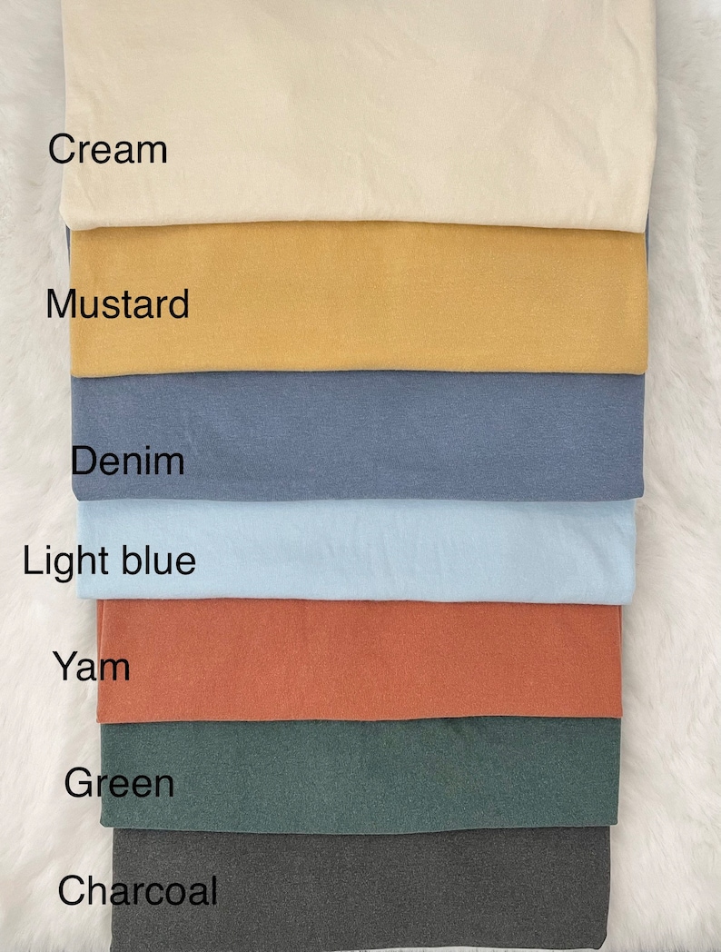 K&ouml;nnte beinhalten: Ein Stapel Stoffmuster in verschiedenen Farben, darunter Creme, Senf, Denim, Hellblau, Yam, Gr&uuml;n und Anthrazit.