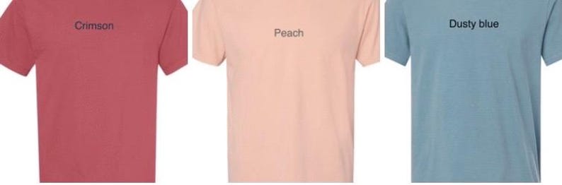 K&ouml;nnte beinhalten: Drei T-Shirts in verschiedenen Farben:  Kirschrot, Pfirsich und staubiges Blau. Jedes Shirt hat ein einzelnes Wort in schwarzer Schrift auf der Vorderseite gedruckt: "Crimson", "Peach" und "Dusty blue".