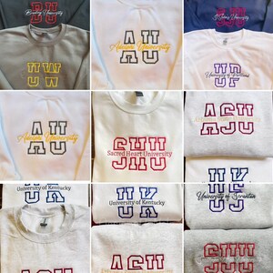 May include: A collection of crewneck sweatshirts featuring embroidered university names and logos. The sweatshirts are in various colors, including gray, white, and navy blue. The embroidered text includes the names of different universities.