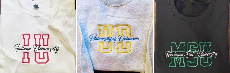 May include: Three sweatshirts with embroidered university logos. The first is white with "IU" and "Indiana University" in red. The second is gray with "UD" and "University of Delaware" in yellow and blue. The third is black with "MSU" and "Michigan State University" in green.