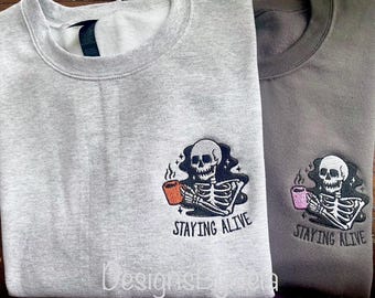 May include: Two gray sweatshirts with a skeleton holding a coffee cup and the text "Staying Alive".