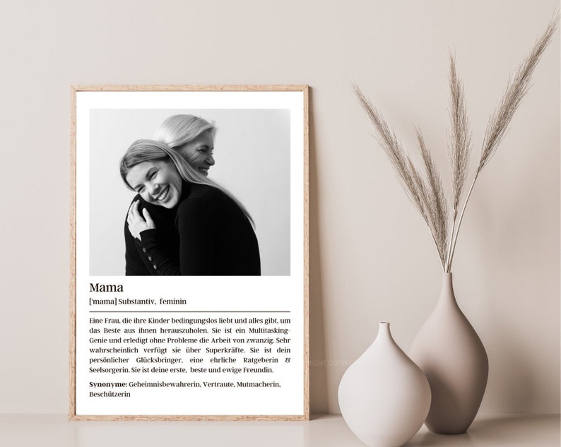 May include: Black and white photo of two women hugging. The photo is framed and has a white background. The text below the photo reads: "Mama ['mama] Substantiv, feminin Eine Frau, die ihre Kinder bedingungslos liebt und alles gibt, um das Beste aus ihnen herauszuholen. Sie ist ein Multitasking Genie und erledigt ohne Probleme die Arbeit von zwanzig. Sehr wahrscheinlich verf&uuml;gt sie &uuml;ber Superkr&auml;fte. Sie ist dein pers&ouml;nlicher Gl&uuml;cksbringer, eine ehrliche Ratgeberin & Seelsorgerin. Sie ist deine erste, beste und ewige Freundin. Synonyme: Geheimnisbewahrerin, Vertraute, Mutmacherin. Besch&uuml;tzerin"